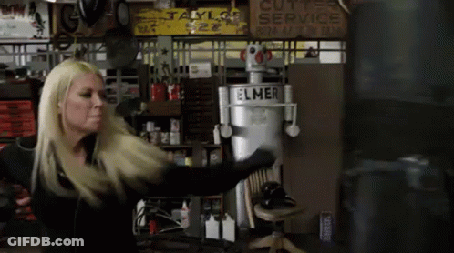 A Woman Is Standing In Front Of A Boxing Bag In A Garage . GIF