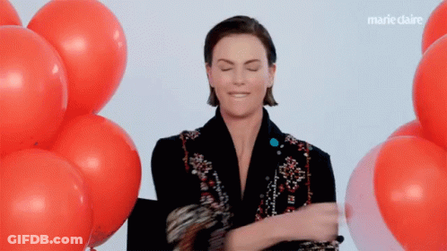 A Woman Is Standing In Front Of A Bunch Of Red Balloons With Marieclaire Written On The Bottom GIF