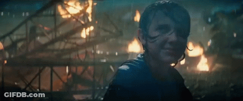 A Woman Is Standing In Front Of A Burning Building In A Dark Room . GIF