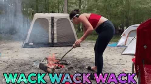 A Woman Is Standing In Front Of A Campfire With The Words Wack Wack Wack On The Bottom GIF