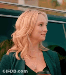 A Woman Is Standing In Front Of A Car Holding A Cup Of Coffee And Smiling . GIF