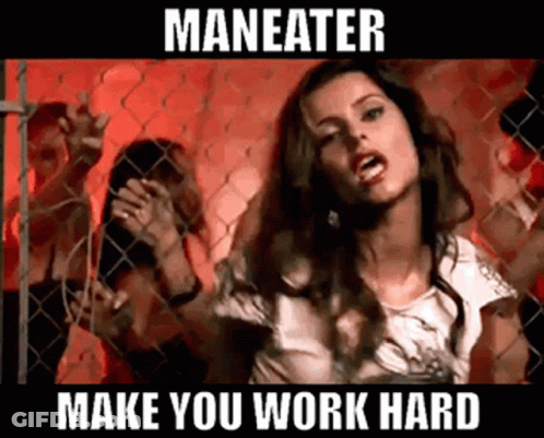 A Woman Is Standing In Front Of A Chain Link Fence With The Words Maneater Make You Work Hard Below Her GIF