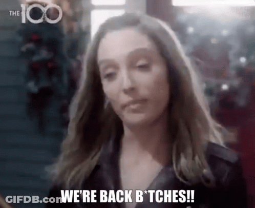 A Woman Is Standing In Front Of A Christmas Tree And Saying `` We 'Re Back Bitches ! '' GIF