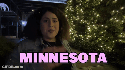 A Woman Is Standing In Front Of A Christmas Tree And The Word Minnesota Is Above Her GIF