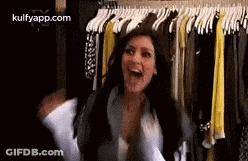 A Woman Is Standing In Front Of A Closet Filled With Clothes And Laughing . GIF