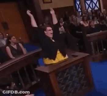 A Woman Is Standing In Front Of A Crowd In A Courtroom . GIF