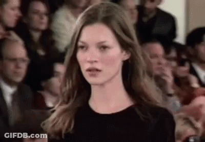 A Woman Is Standing In Front Of A Crowd Of People . GIF