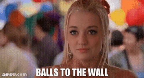 A Woman Is Standing In Front Of A Crowd Of People With Balloons And Says Balls To The Wall . GIF