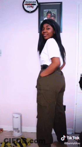 A Woman Is Standing In Front Of A Danger Zone Sign GIF
