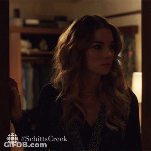 A Woman Is Standing In Front Of A Door With #Schitts Creek Written On The Bottom GIF