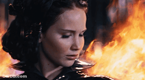 A Woman Is Standing In Front Of A Fire GIF
