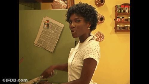 A Woman Is Standing In Front Of A Green Refrigerator With A Newspaper On The Door GIF
