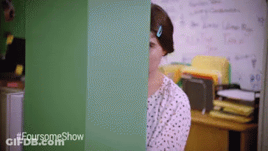 A Woman Is Standing In Front Of A Green Wall With The Words Foursomeshow Written On It GIF