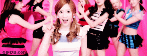 A Woman Is Standing In Front Of A Group Of Dancers . GIF