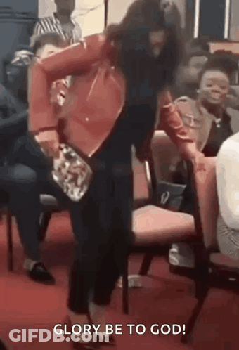 A Woman Is Standing In Front Of A Group Of People In A Church And Dancing . GIF