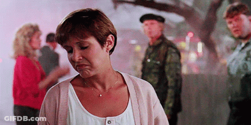 A Woman Is Standing In Front Of A Group Of People With A Man In A Military Uniform Standing Behind Her . GIF
