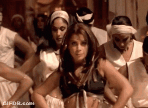 A Woman Is Standing In Front Of A Group Of Women Dancing In A Room . GIF