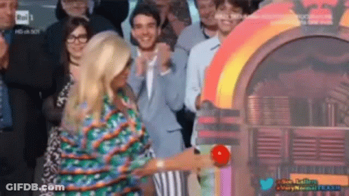 A Woman Is Standing In Front Of A Jukebox In A Crowd Of People GIF