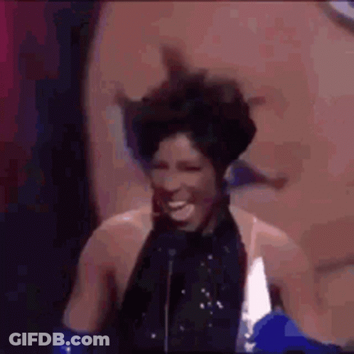 A Woman Is Standing In Front Of A Microphone And Laughing . GIF