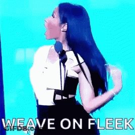 A Woman Is Standing In Front Of A Microphone With The Words `` Weave On Fleek '' Written On The Screen . GIF