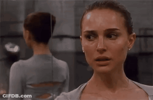 A Woman Is Standing In Front Of A Mirror And Looking At Herself . GIF