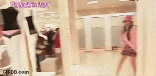 A Woman Is Standing In Front Of A Mirror In A Dressing Room In A Store . GIF