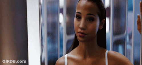 A Woman Is Standing In Front Of A Mirror Looking At Herself . GIF