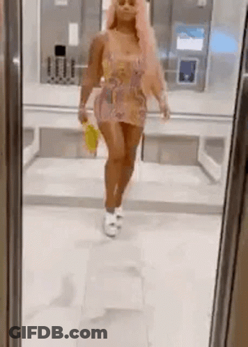 A Woman Is Standing In Front Of A Mirror Wearing A Dress And Holding A Yellow Bag . GIF