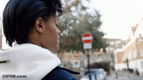 A Woman Is Standing In Front Of A No Entry Sign GIF