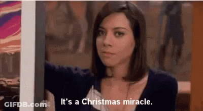 A Woman Is Standing In Front Of A Picture And Says `` It 'S A Christmas Miracle . '' GIF