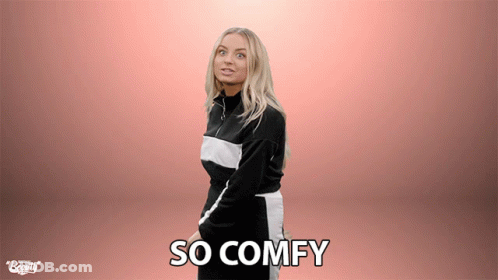 A Woman Is Standing In Front Of A Pink Background With The Words So Comfy Written On It GIF