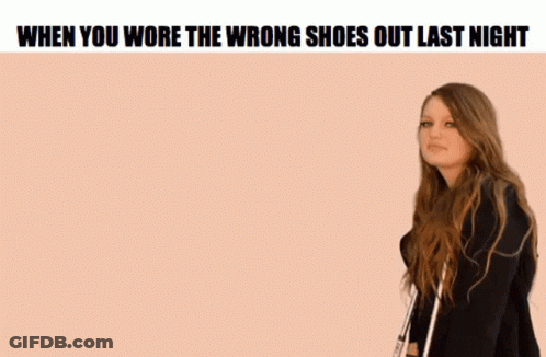 A Woman Is Standing In Front Of A Pink Background With The Words `` When You Wore The Wrong Shoes Out Last Night '' On I GIF