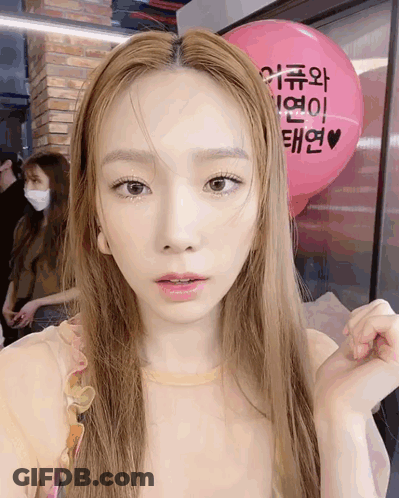 A Woman Is Standing In Front Of A Pink Balloon That Says ' I Love You ' On It GIF