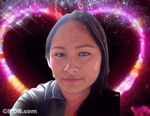 A Woman Is Standing In Front Of A Pink Heart Shaped Background GIF