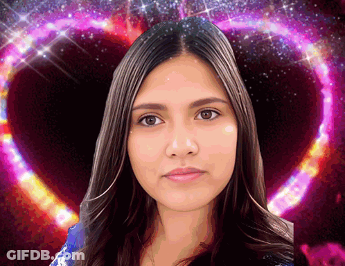 A Woman Is Standing In Front Of A Pink Heart Shaped Background GIF