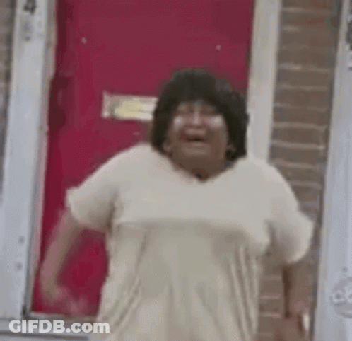 A Woman Is Standing In Front Of A Red Door Laughing . GIF
