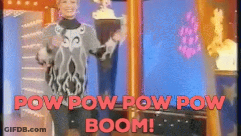 A Woman Is Standing In Front Of A Screen That Says Pow Pow Pow Boom GIF