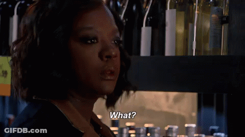 A Woman Is Standing In Front Of A Shelf With Wine Bottles And Says What . GIF