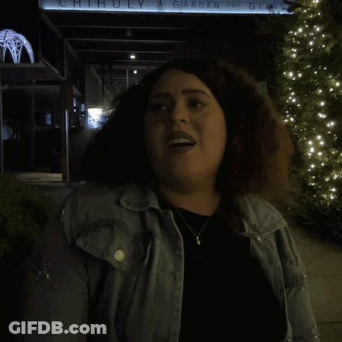 A Woman Is Standing In Front Of A Sign That Says Alright GIF