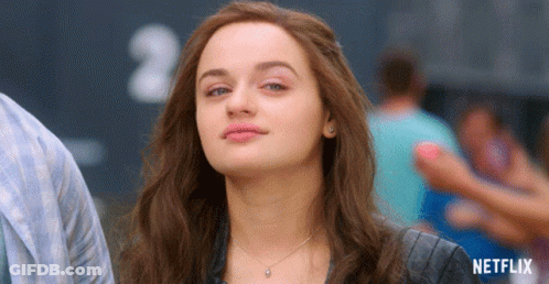 A Woman Is Standing In Front Of A Sign That Says Netflix On It GIF