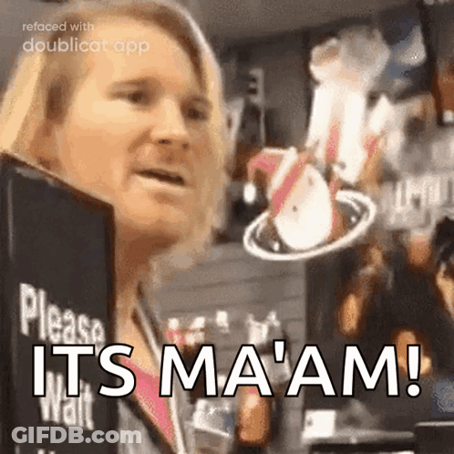 A Woman Is Standing In Front Of A Sign That Says Please Wait It 'S Ma 'Am GIF