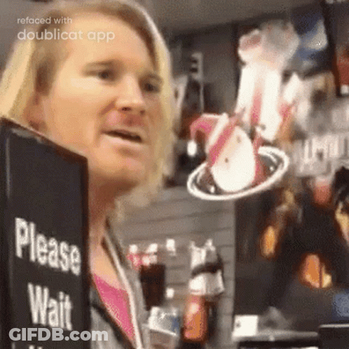 A Woman Is Standing In Front Of A Sign That Says Please Wait . GIF