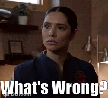 A Woman Is Standing In Front Of A Sign That Says " What 'S Wrong " GIF