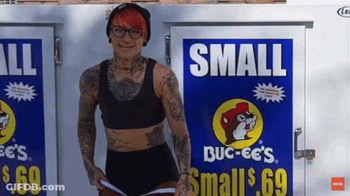 A Woman Is Standing In Front Of A Small Buck-Ee 'S Sign GIF