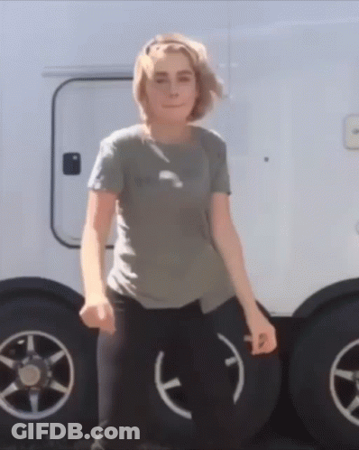 A Woman Is Standing In Front Of A Trailer With A Smiley Face On The Tire GIF