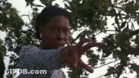 A Woman Is Standing In Front Of A Tree And Pointing At The Camera . GIF