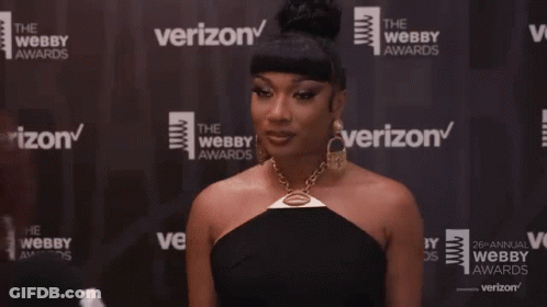 A Woman Is Standing In Front Of A Verizon Banner GIF