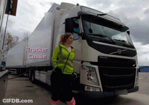 A Woman Is Standing In Front Of A Volvo Truck With The Name Trucker Cassie Written On It GIF