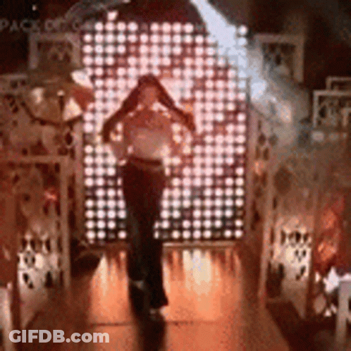 A Woman Is Standing In Front Of A Wall Of Lights In A Dark Room . GIF