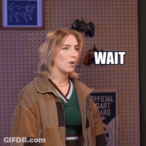 A Woman Is Standing In Front Of A Wall That Says Wait Wait GIF